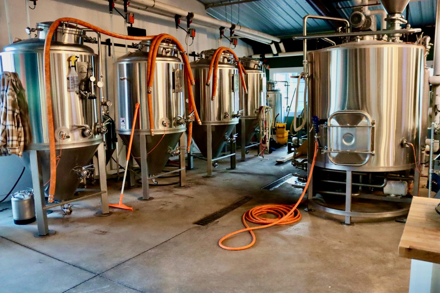 Craft brewery interior with four stainless steel fermentation tanks and glycol hoses